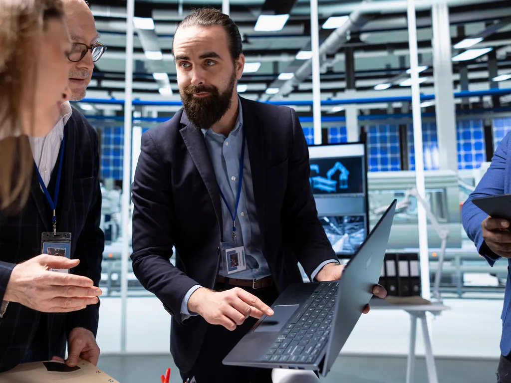 Equipo técnico revisando una laptop en una planta de manufactura avanzada