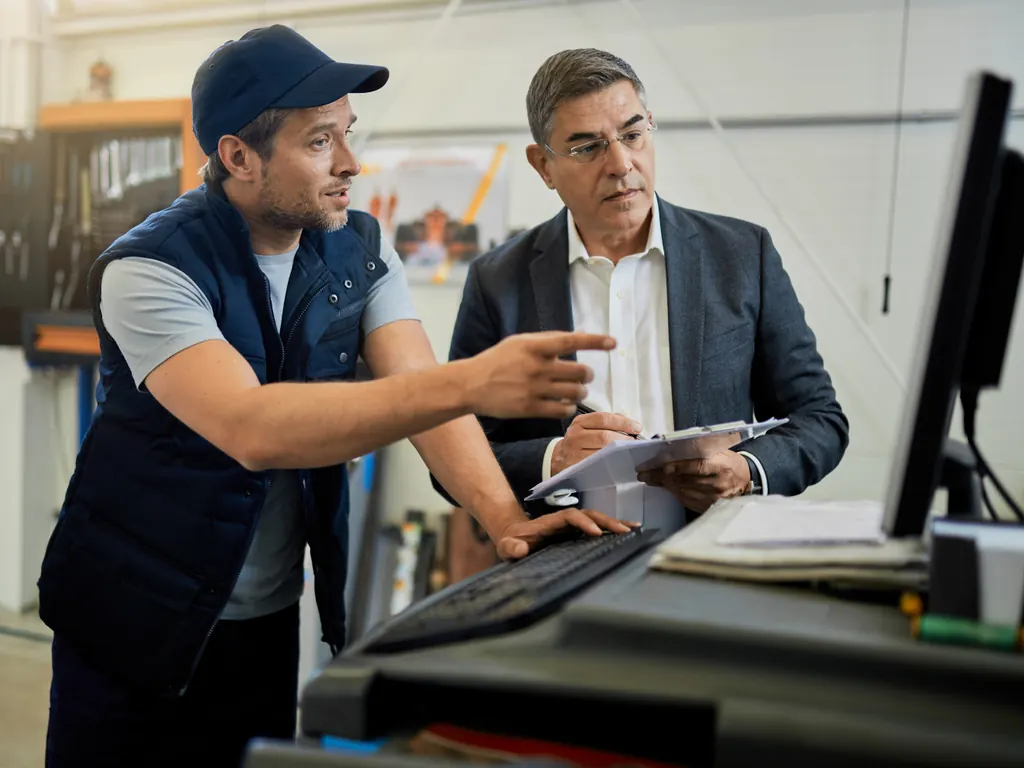 Técnico y supervisor revisando una orden de servicio en un taller